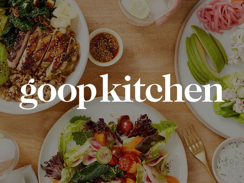 goop Kitchen logo over and image of fresh grilled chicken bowls, mixed green salads, and veggies on a wood table.